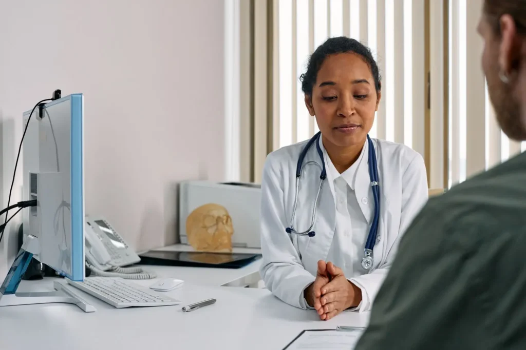 Woman in white suit with stethoscope talking to a person